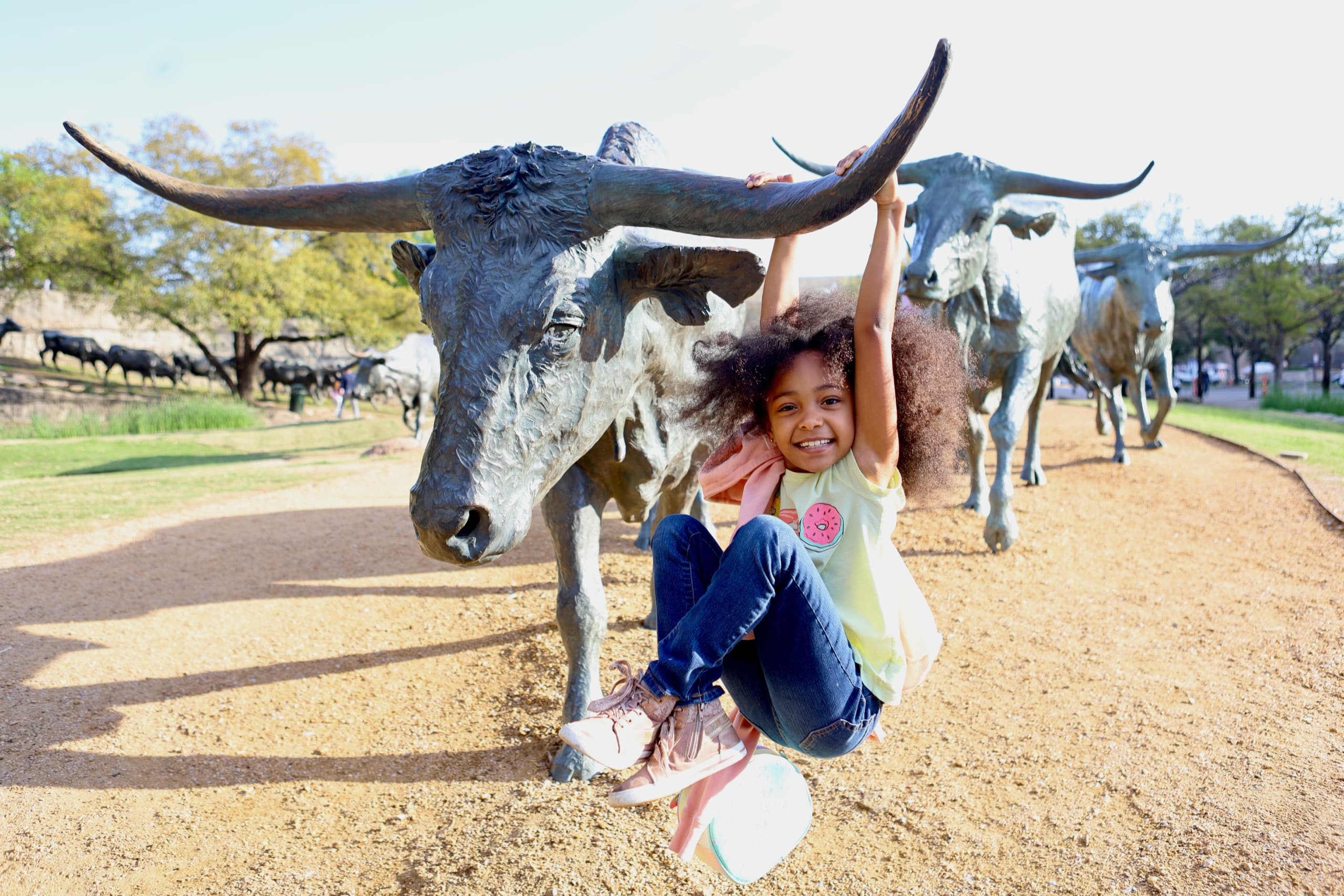 Young girl sitting under bull statue