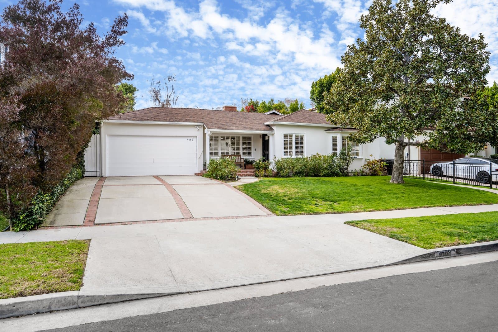 Welcoming single-story home with a green lawn and mature trees
